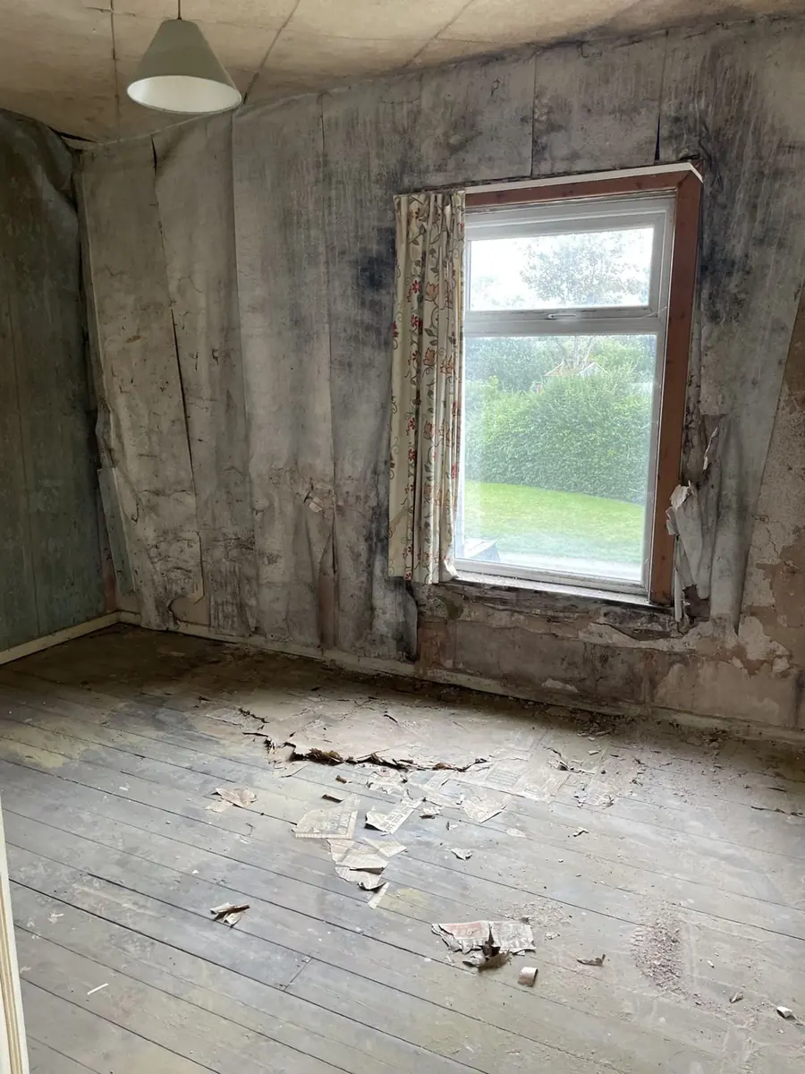 Empty room with peeling wallpaper and bare floorboards requiring full modernisation