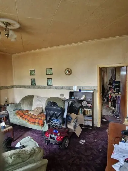 Living room of a purchased property filled with furniture, boxes and belongings