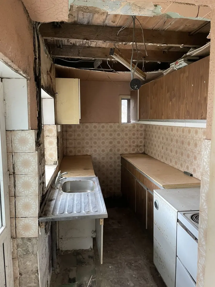 Dated kitchen with missing ceiling panels and exposed wiring requiring full refurbishment