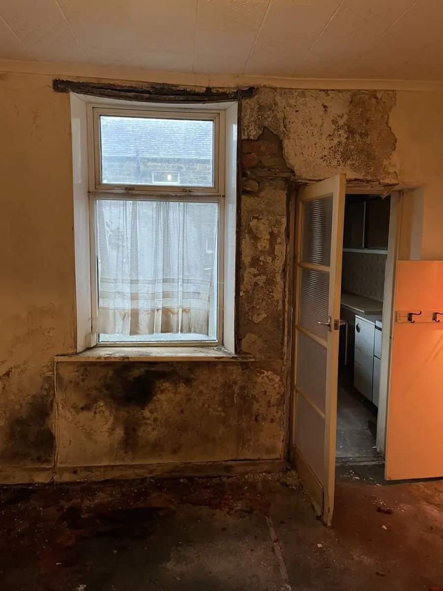 Room with damp-stained walls and dated fittings requiring major repairs